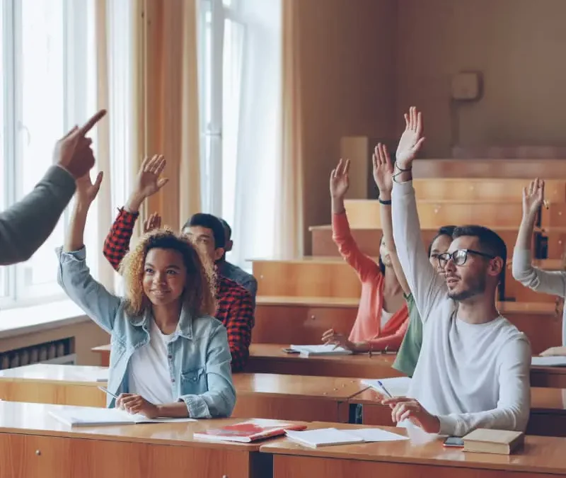 students raising their hands in class